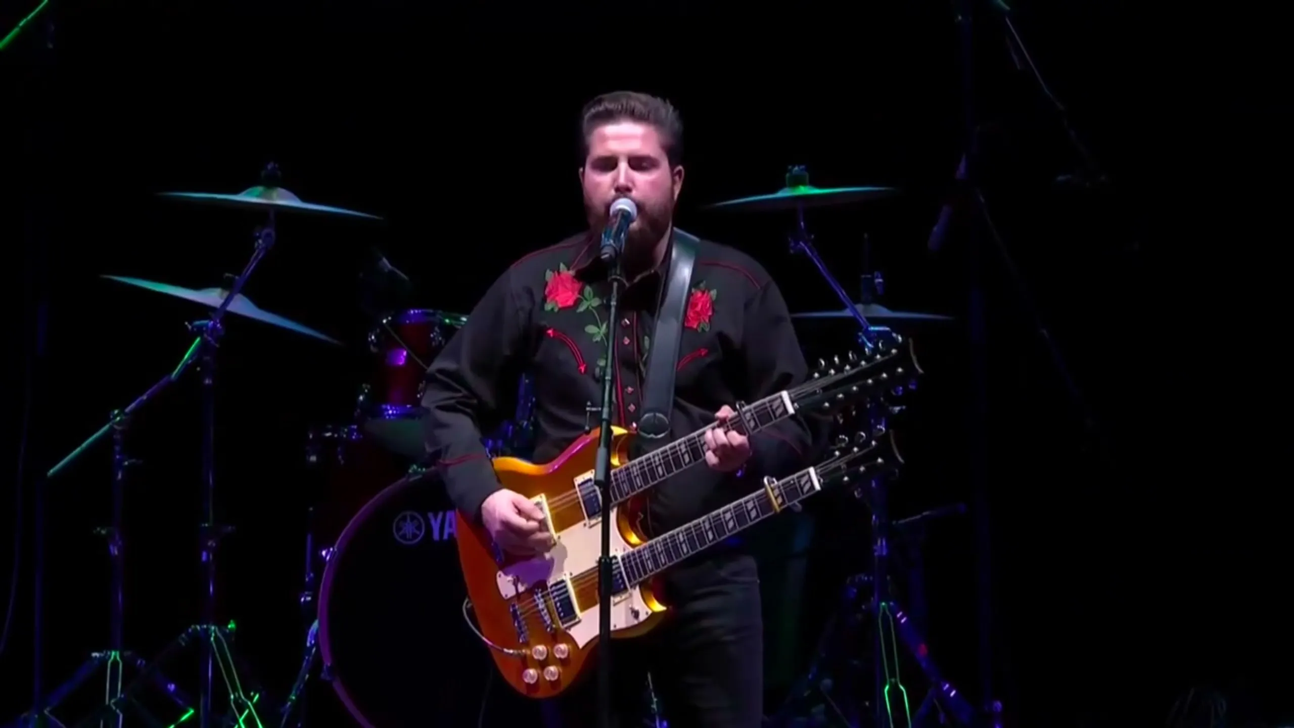 JJ Fuentes cantando con una guitarra de doble mástil en el escenario del WiZink Center